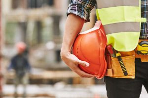 Tradie holding protective hat on a construction site