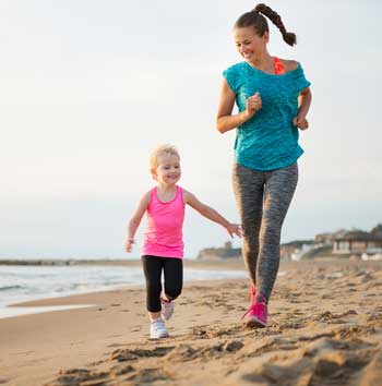 Mother and daughter running on the beach