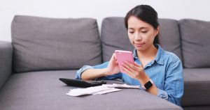 Young woman taking photos of receipts with her phone