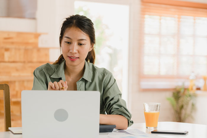 Asian lady using her laptop to do her record keeping