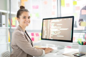 Young woman sitting in front of a computer smiling