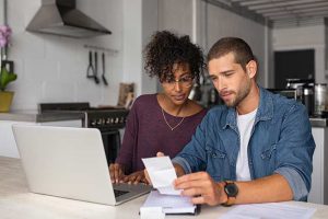 Young couple looking at receipts in front of a computer