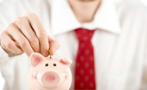 Businessman putting coins into a piggy bank