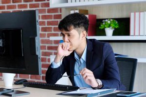 Young man looking confused and unhappy at his computer