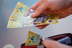 Hands pulling Australian cash out of a wallet