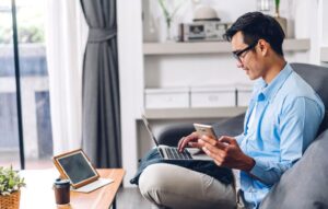 Young smiling man relaxing using laptop computer working and video conference meeting at home.