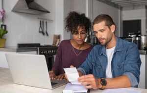 Young couple looking at their computer and documents to find out what effect the Stage 3 tax cuts have on them