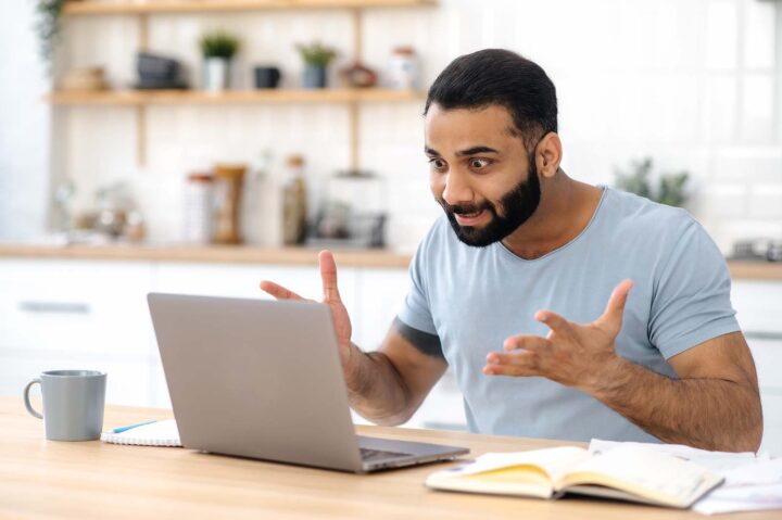 Man is upset with his laptop screen because he is wondering why his tax refund is so low