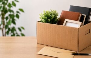 Redundancy Tax: Cardboard box packed with notebooks on desk